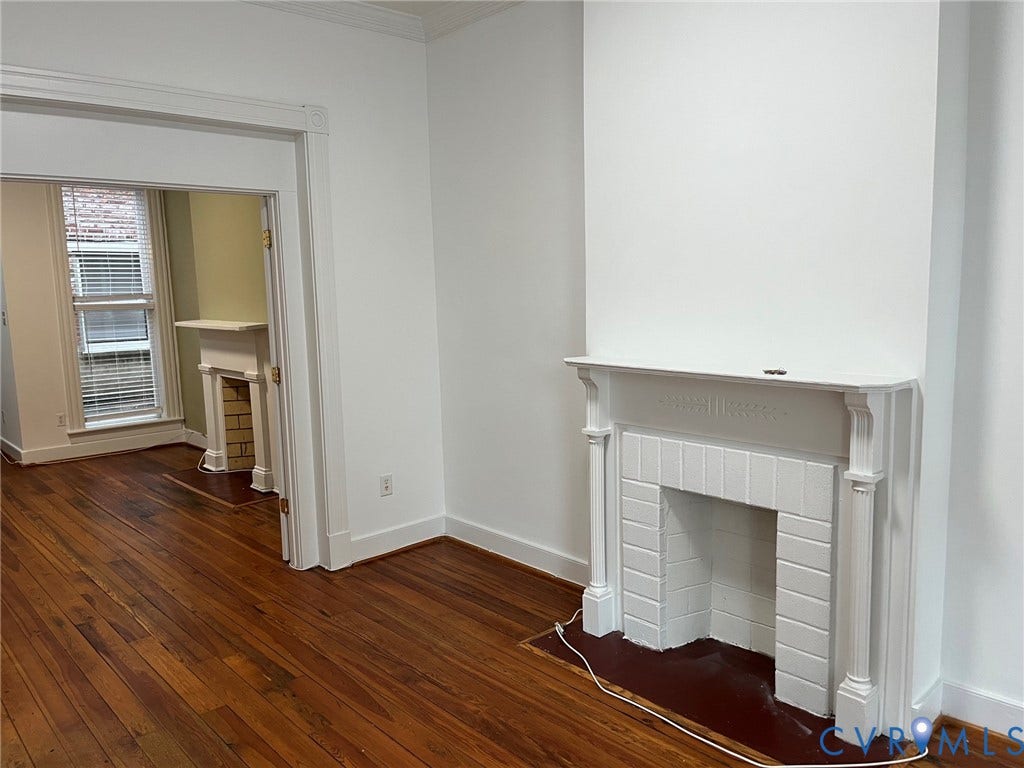 220 W Marshall Street, Jackson Ward, Richmond, VA 23220 Living area featuring wood-finish flooring, a decorative fireplace with a white mantel and tiled surround, and a cased opening