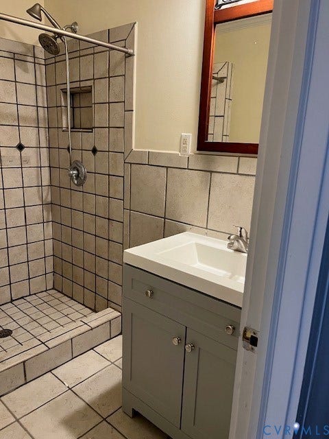 220 W Marshall Street, Jackson Ward, Richmond, VA 23220 Bathroom featuring a tiled shower with a built-in niche, a vanity with an integrated sink, and a framed mirror