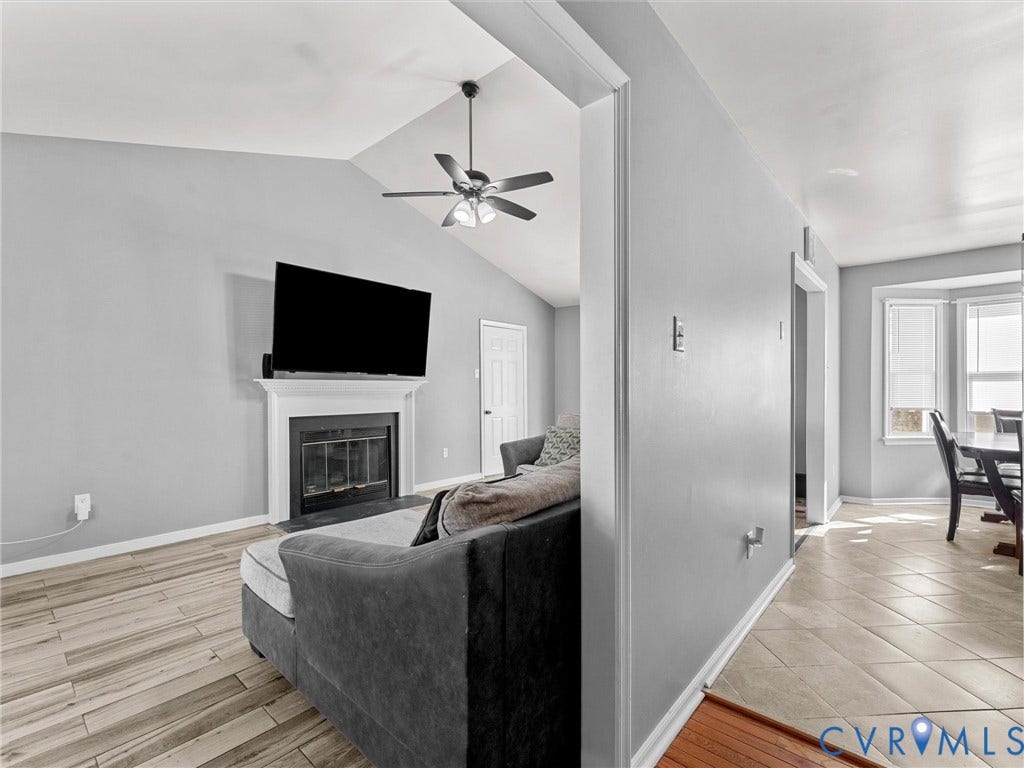 7323 Pineleaf Drive, Chesterfield, VA 23234 Vaulted ceiling living area featuring a fireplace with a white mantel, wood-finish flooring, and a ceiling fan