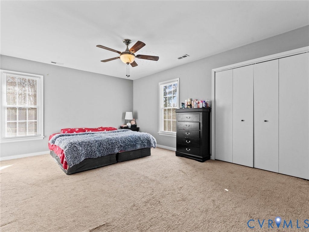 7323 Pineleaf Drive, Chesterfield, VA 23234 Spacious room featuring neutral carpeting, light gray walls, two windows, a ceiling fan with integrated lighting, and a multi-panel closet with white doors