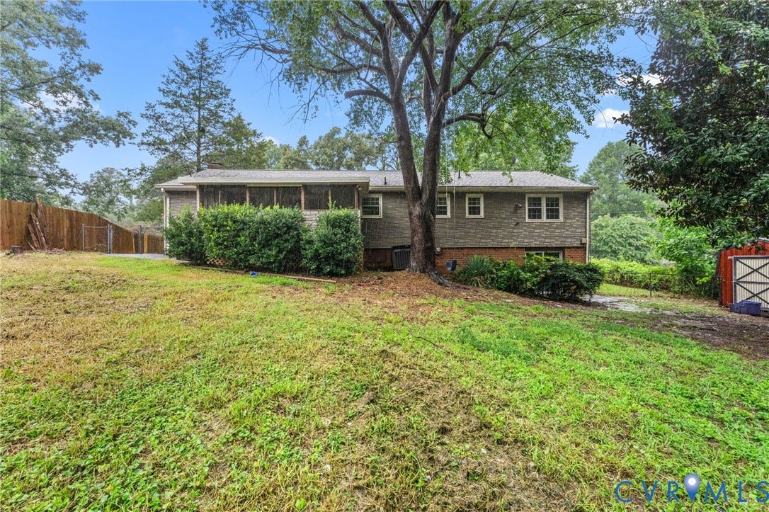 Expansive backyard featuring mature trees, a screened-in porch, privacy fencing, and exterior siding with brick detailing
