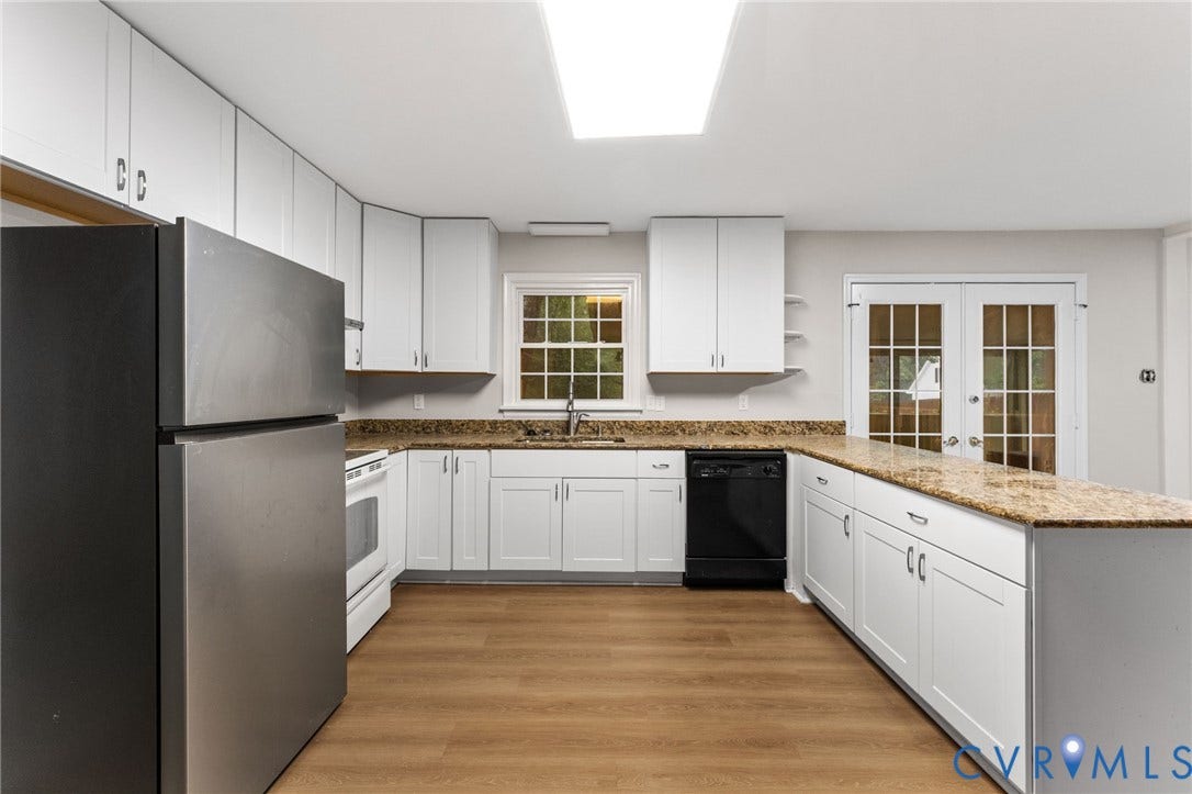 Kitchen featuring extensive white cabinetry, light-toned wood-finish flooring, a stainless steel refrigerator, and granite countertops