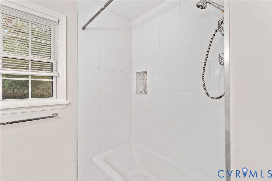 Bathtub-shower combination featuring white subway tile surround, a mosaic-tiled shower niche, and a chrome shower head with a handheld sprayer