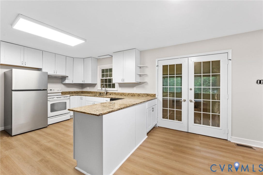 Kitchen featuring white cabinetry, light-toned countertops, a stainless steel refrigerator, a white range, and wood-finish flooring