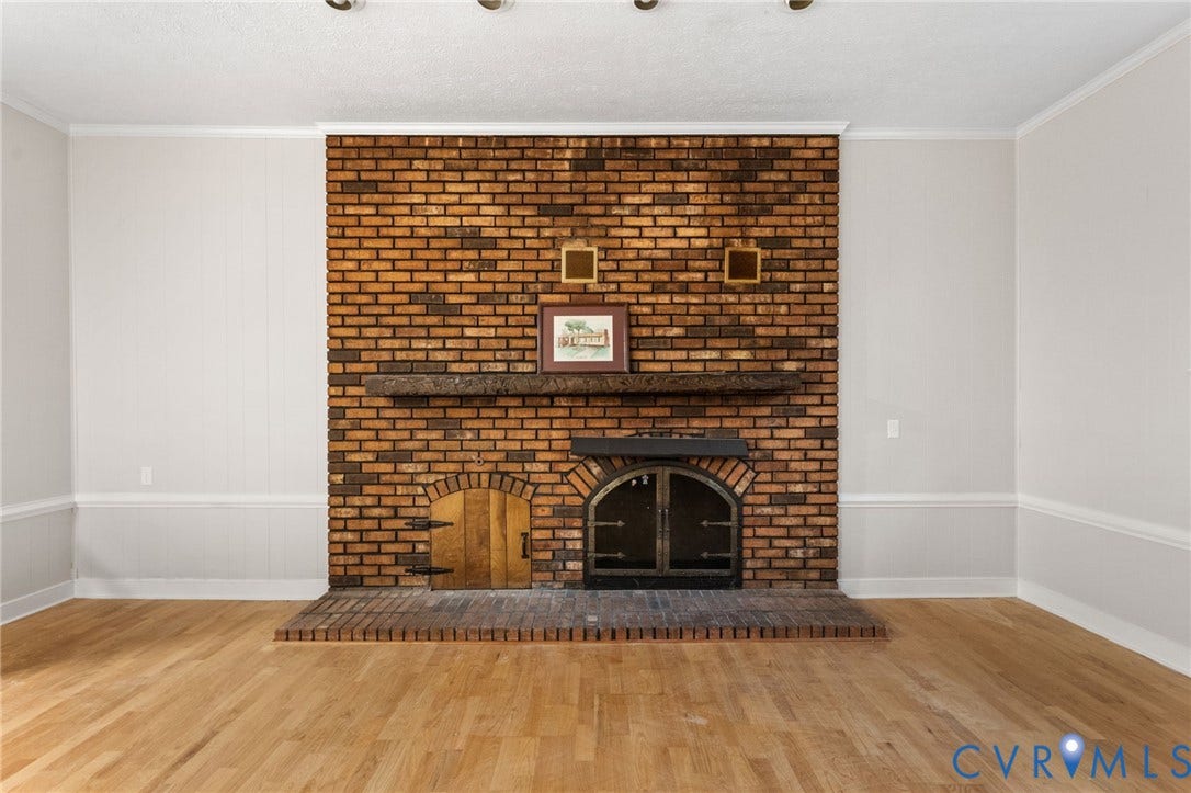 Brick fireplace featuring an arched firebox with iron doors and a wood mantel
