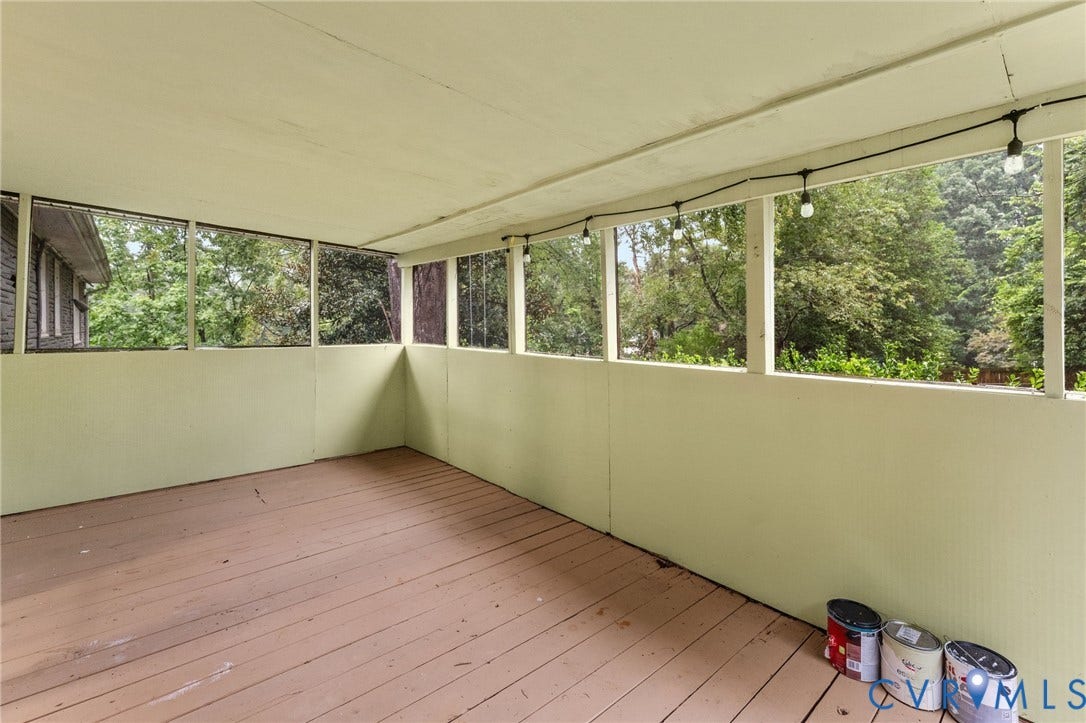 Expansive screened-in porch featuring wood-finish flooring and string lighting