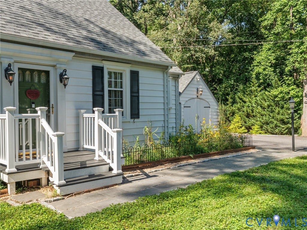 White siding exterior with a dark shingle roof, featuring a front porch with white railings and dark steps