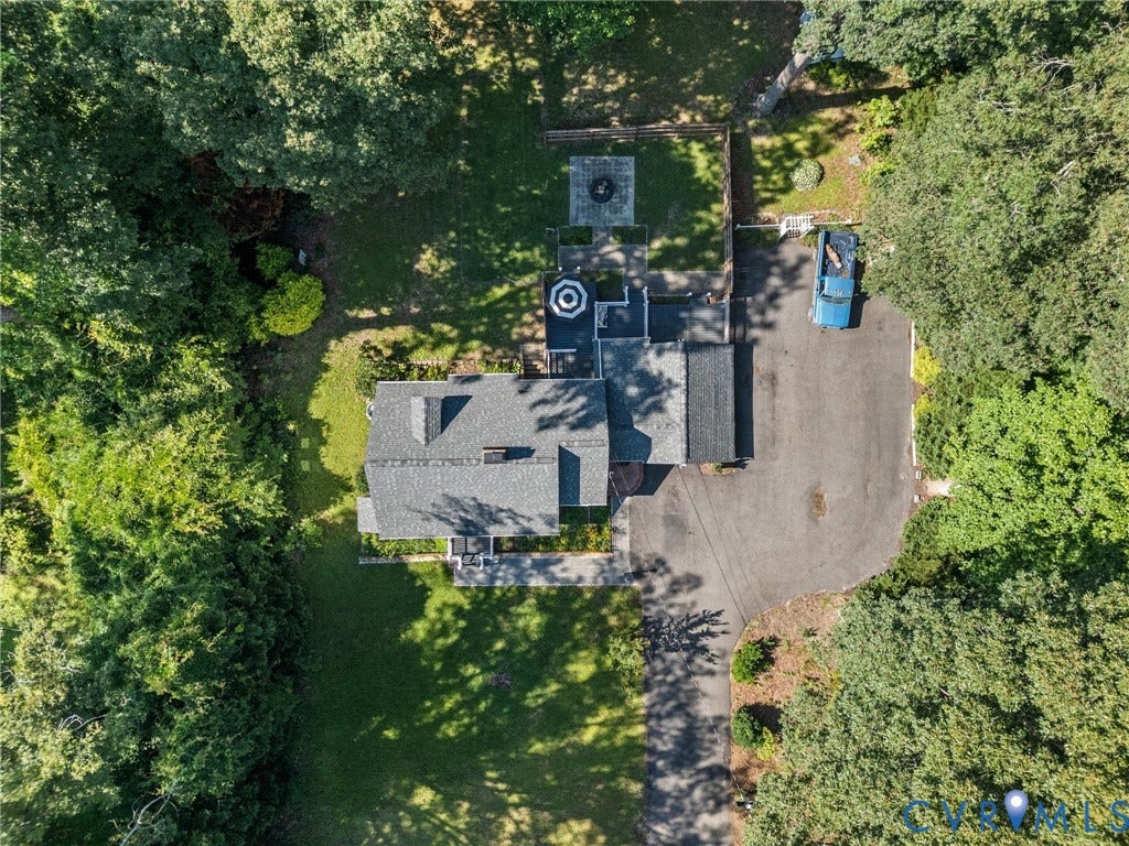Expansive property featuring a asphalt driveway, mature trees, a stone patio, and a fire pit area