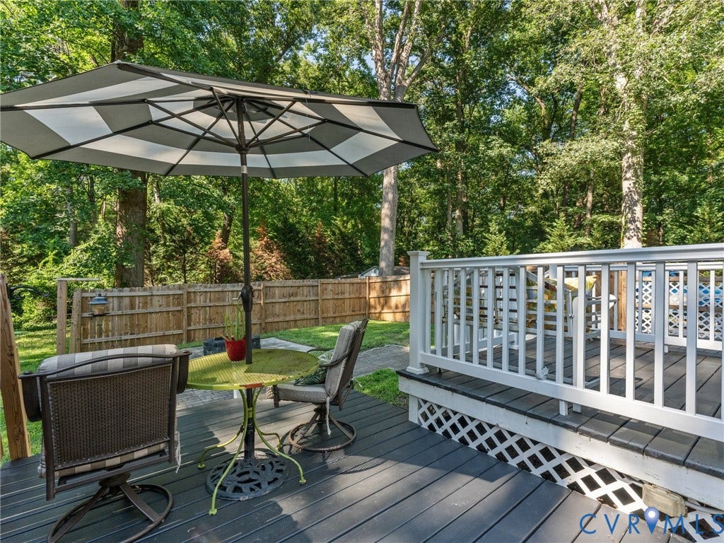 Outdoor deck featuring dark-stained wood-finish flooring with white lattice skirting and matching white railings