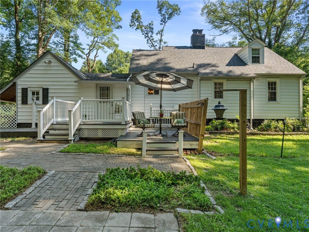 Rear exterior featuring white siding, a multi-level deck, and a brick paver patio