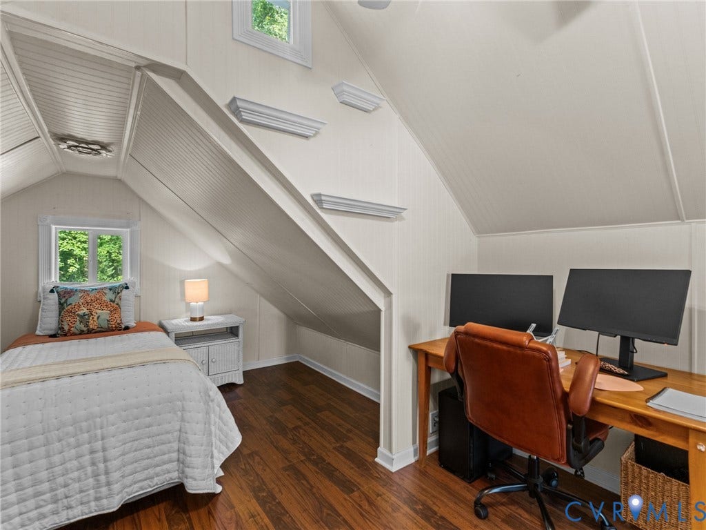 Attic room featuring rich wood-finish flooring, white paneled walls, and a recessed window