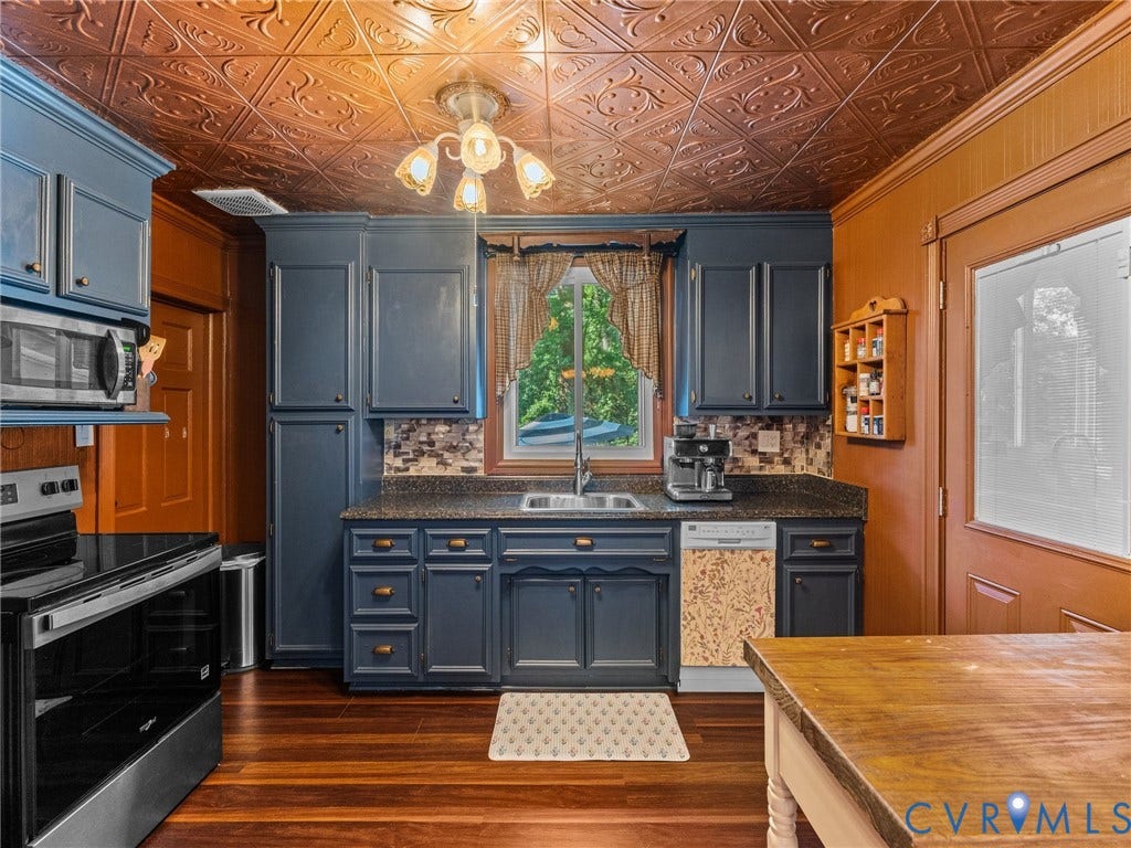 Kitchen featuring a patterned ceiling, wood-finish flooring, dark cabinetry, and a mosaic tile backsplash