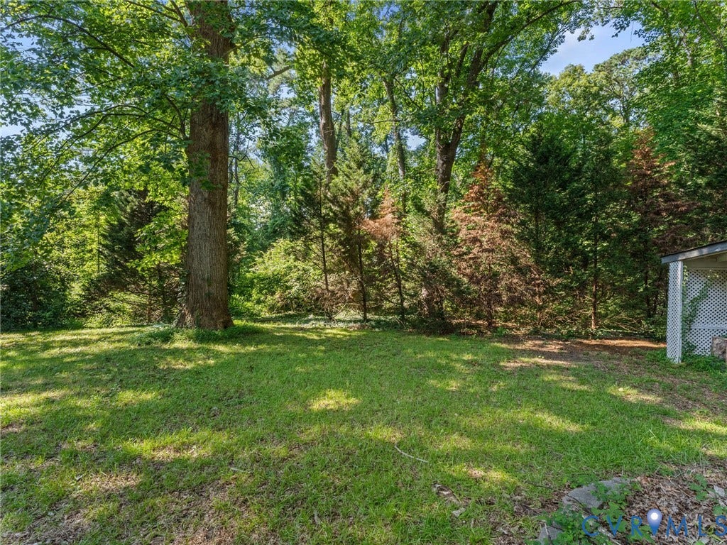Expansive green lawn framed by mature trees and varied foliage
