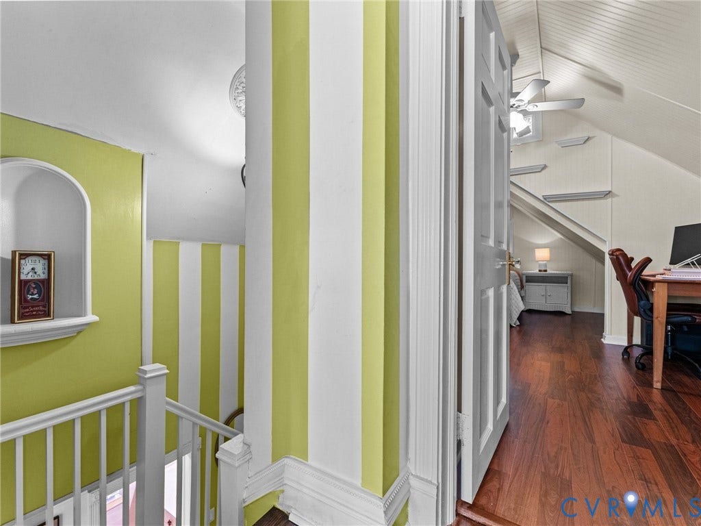 Landing area featuring a built-in arched alcove, white painted railing, and accent wall with vertical white and lime green stripes