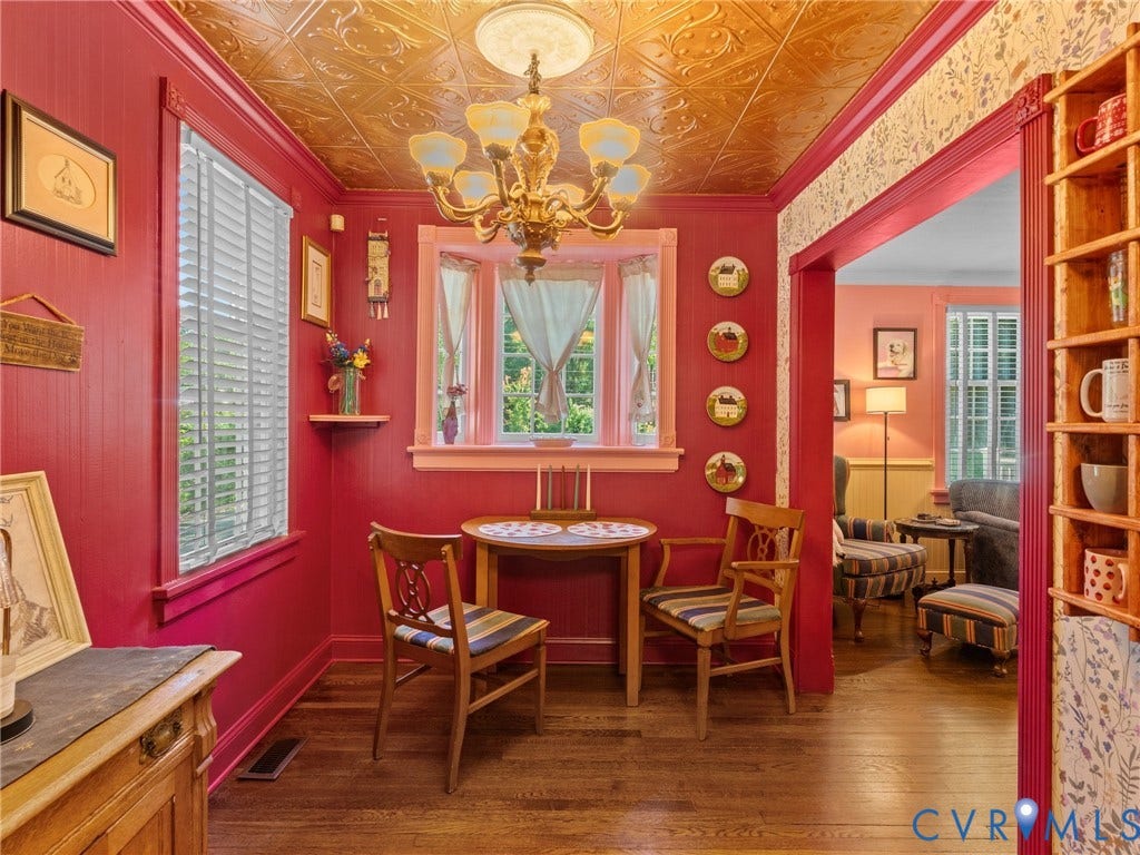 Dining area featuring rich red paneling, wood-finish flooring, and a decorative gold-toned ceiling