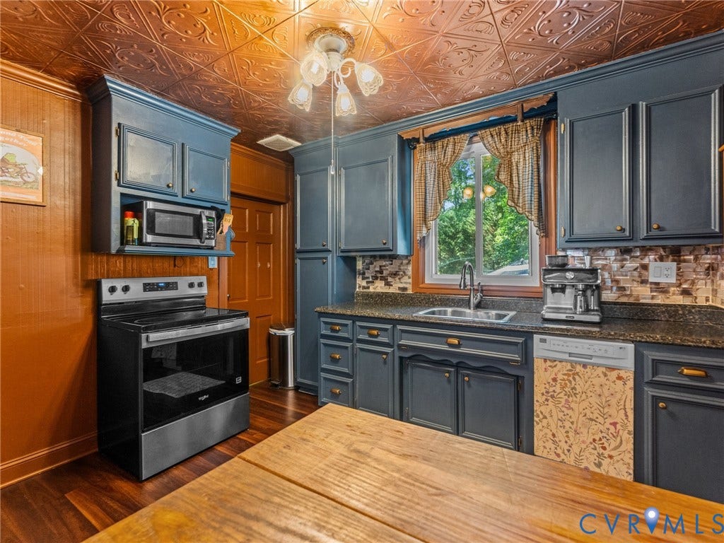 Kitchen featuring a pressed copper-finish ceiling, wood-finish flooring, dark blue cabinetry, stone-finish countertops, and a mosaic tile backsplash