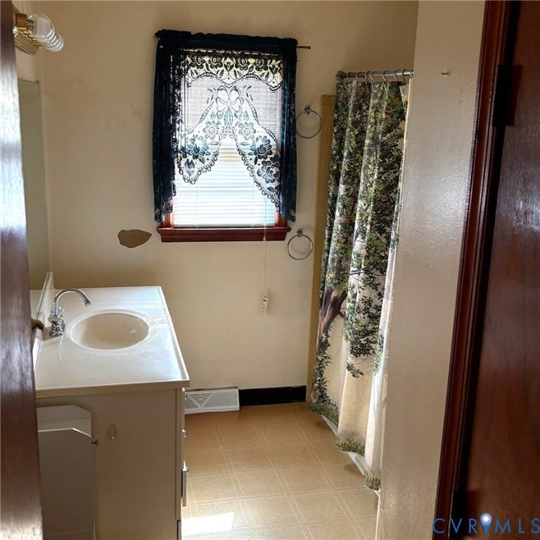 Bathroom featuring a vanity with an integrated sink, polished chrome faucet, and under-sink cabinetry