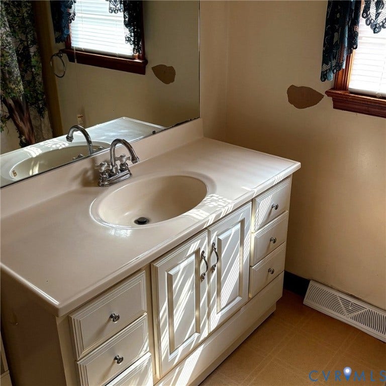 Bathroom vanity featuring a sink with a chrome faucet and storage cabinet