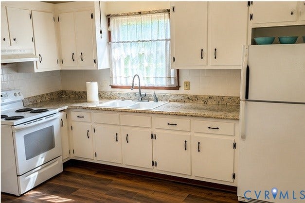 Kitchen featuring white cabinetry, wood-finish flooring, a double basin sink with a gooseneck faucet, white appliances, and a tiled backsplash