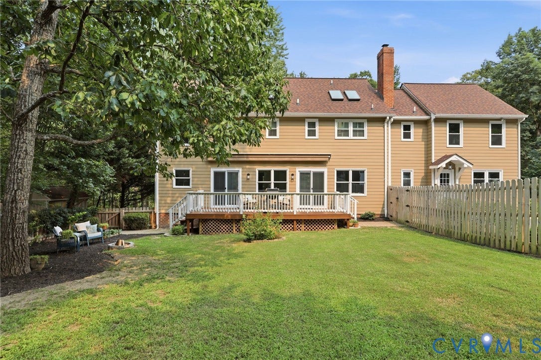 2904 Old Gun Rd W, Old Gun, Midlothian, VA 23113 Expansive rear exterior featuring a large wooden deck with white railings, multiple sliding glass doors, a brick chimney, and a picket fence