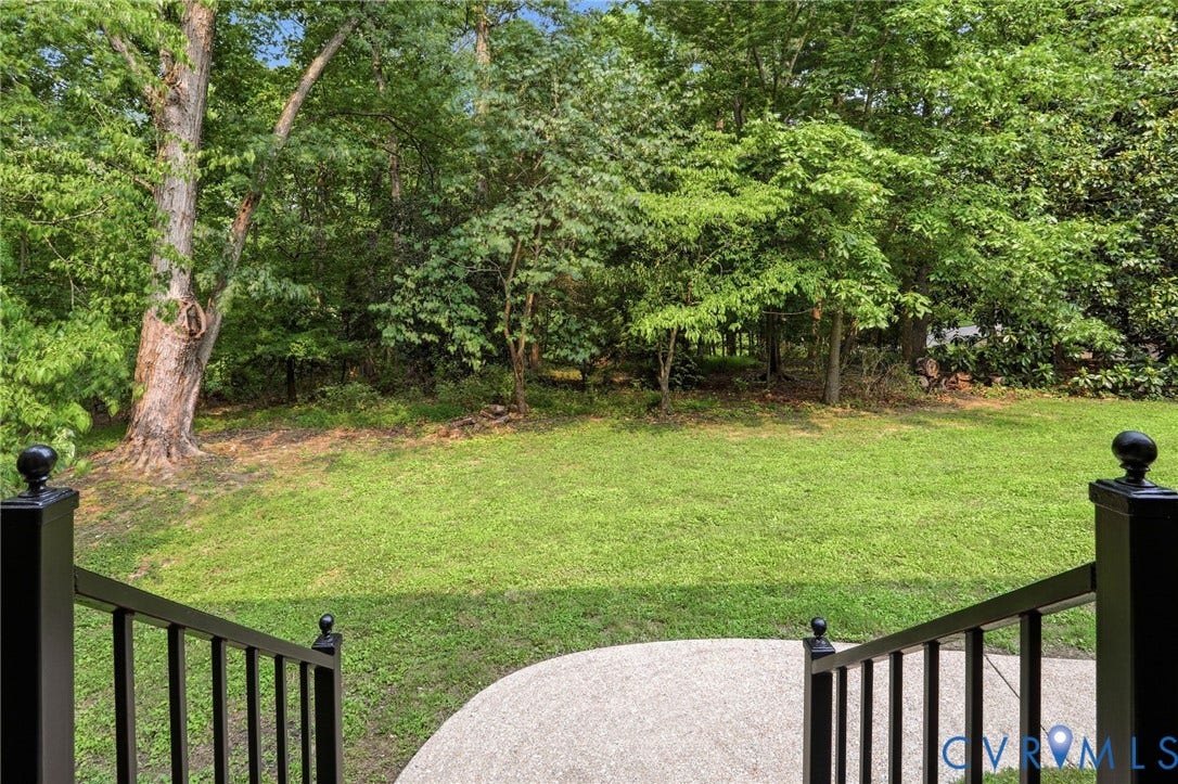 2904 Old Gun Rd W, Old Gun, Midlothian, VA 23113 Expansive green lawn surrounded by mature trees, featuring a concrete patio and black metal railings