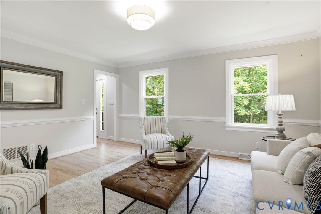 2904 Old Gun Rd W, Old Gun, Midlothian, VA 23113 Bright living space featuring light wood-finish flooring, two large windows, white wainscoting, crown molding, and a flush mount ceiling light fixture