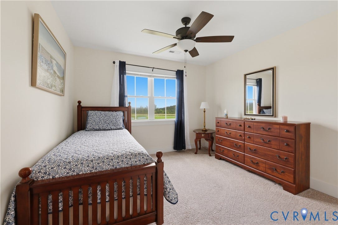 25181 W Soap Stone Rd, Amelia, VA 23083 Carpeted room with a ceiling fan, a double-hung window with dark curtains, and light-toned walls