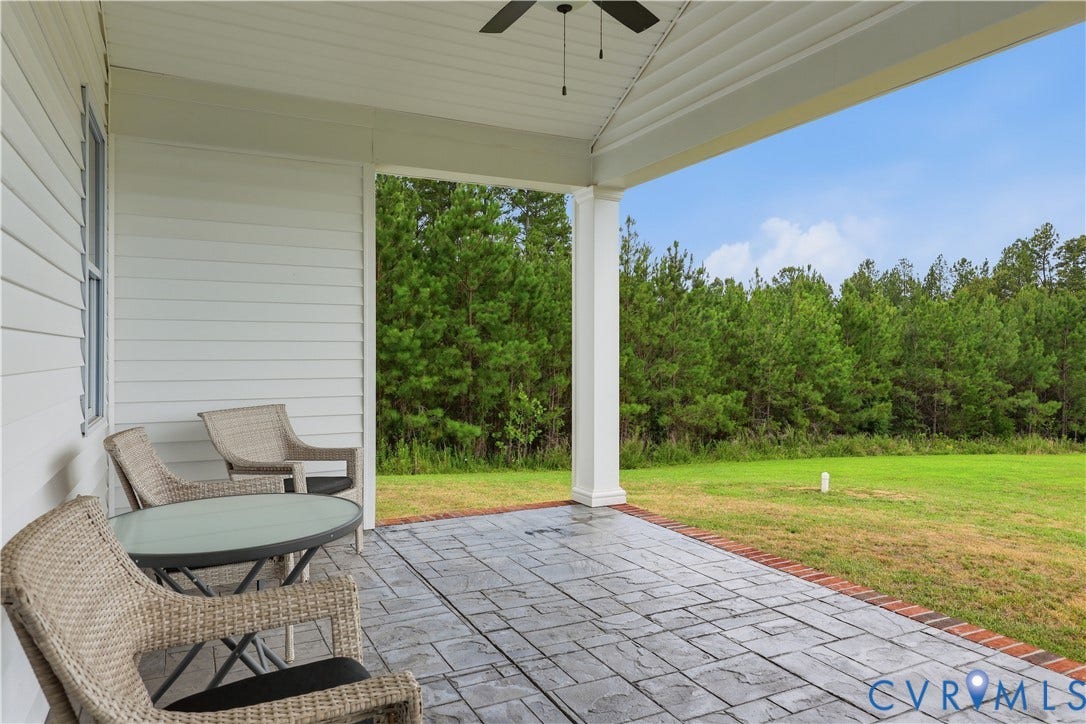 25181 W Soap Stone Rd, Amelia, VA 23083 Covered patio featuring stamped concrete flooring, brick edging, a ceiling fan, and a view of mature trees