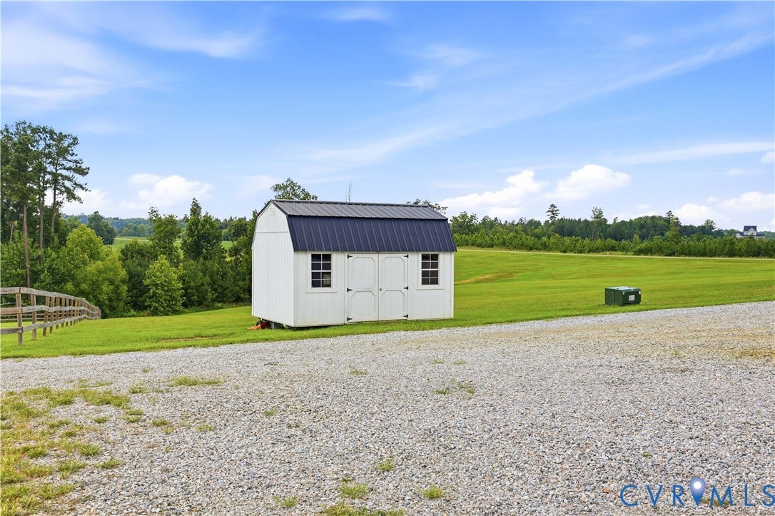25181 W Soap Stone Rd, Amelia, VA 23083 White storage shed featuring a dark metal gambrel roof and two windows