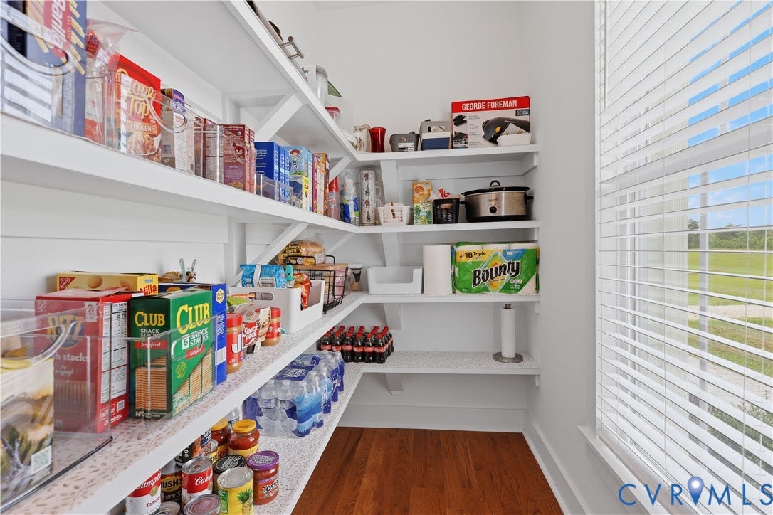 25181 W Soap Stone Rd, Amelia, VA 23083 Spacious pantry featuring extensive built-in white shelving, wood-finish flooring, and a large window with privacy blinds