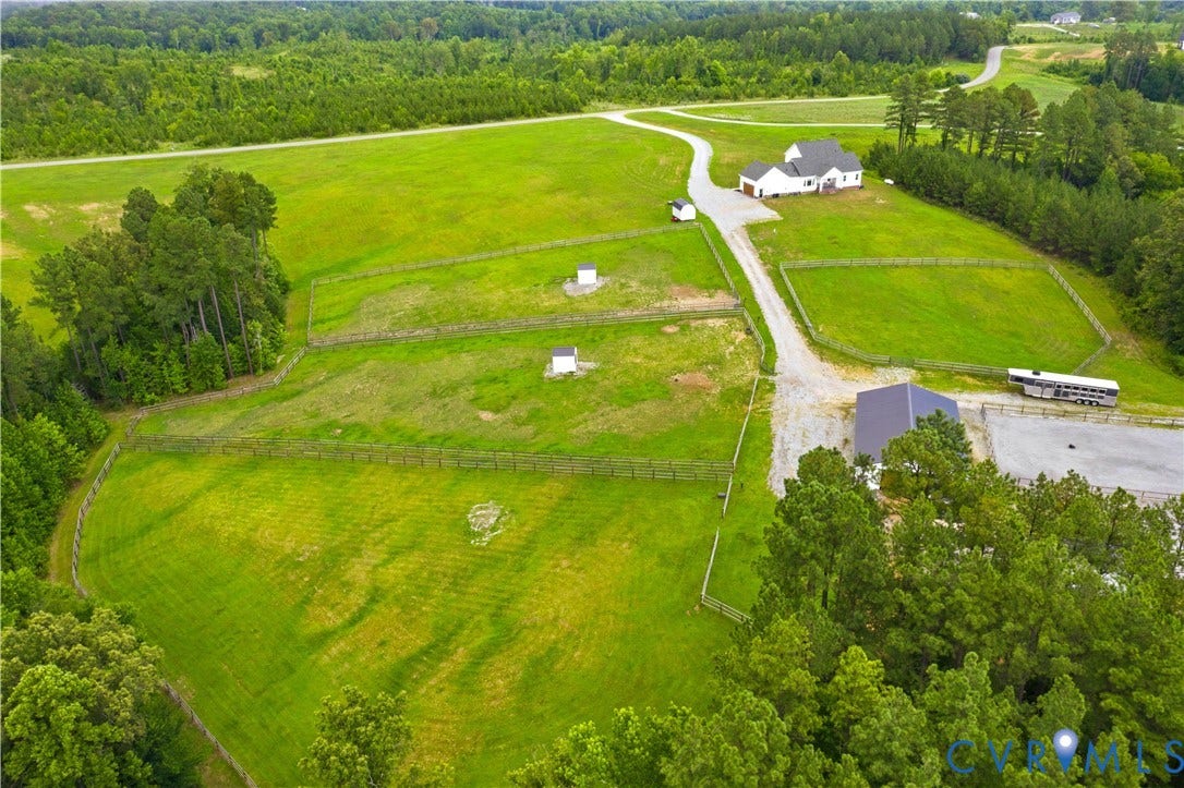 25181 W Soap Stone Rd, Amelia, VA 23083 Expansive property featuring a white single-story residence, multiple fenced pastures, a large grey barn, and a gravel drive