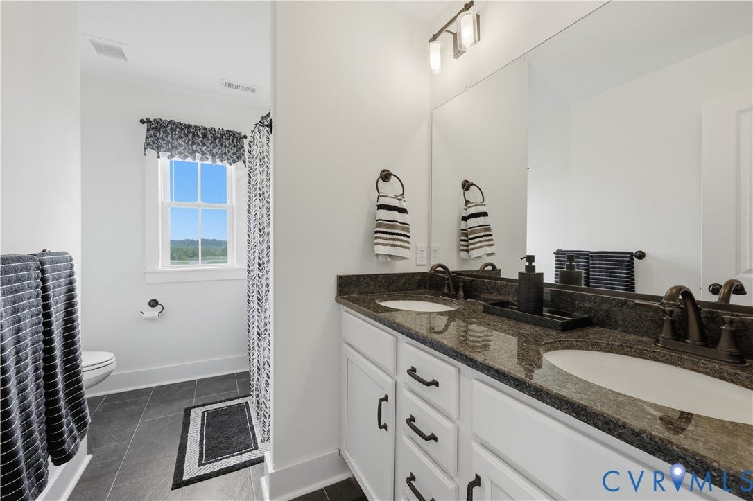 25181 W Soap Stone Rd, Amelia, VA 23083 Double vanity with dark stone countertop, white cabinetry, and brushed bronze fixtures