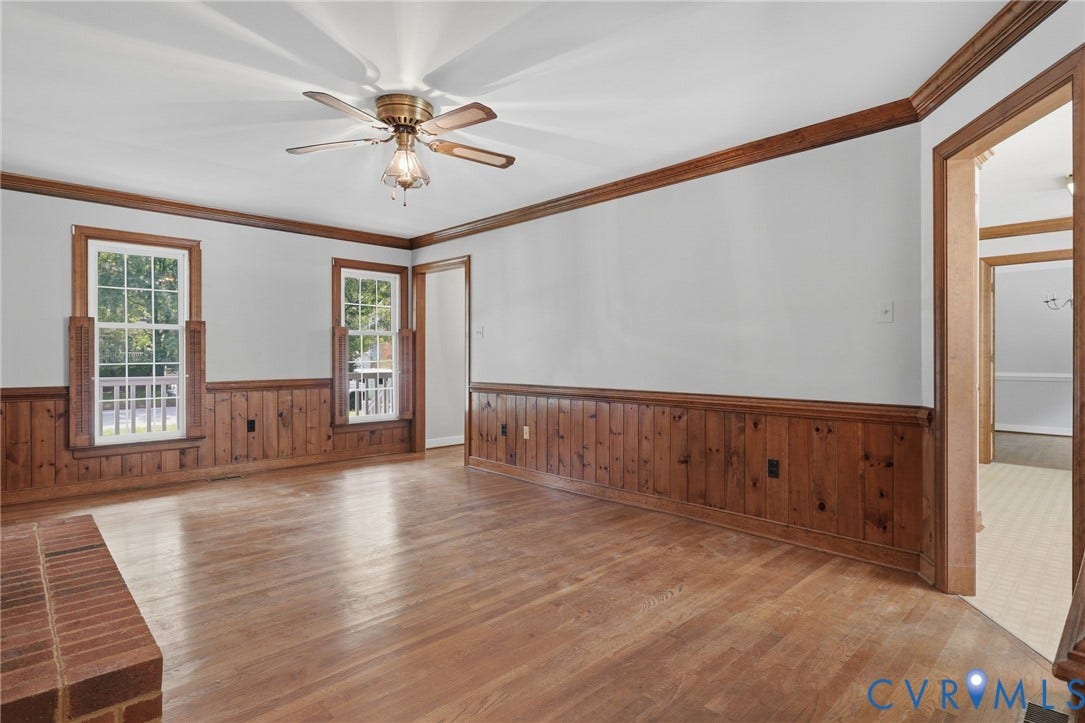 Second view of the spacious family room showcasing hardwood floors, wood trim, and access to the adjoining rooms.