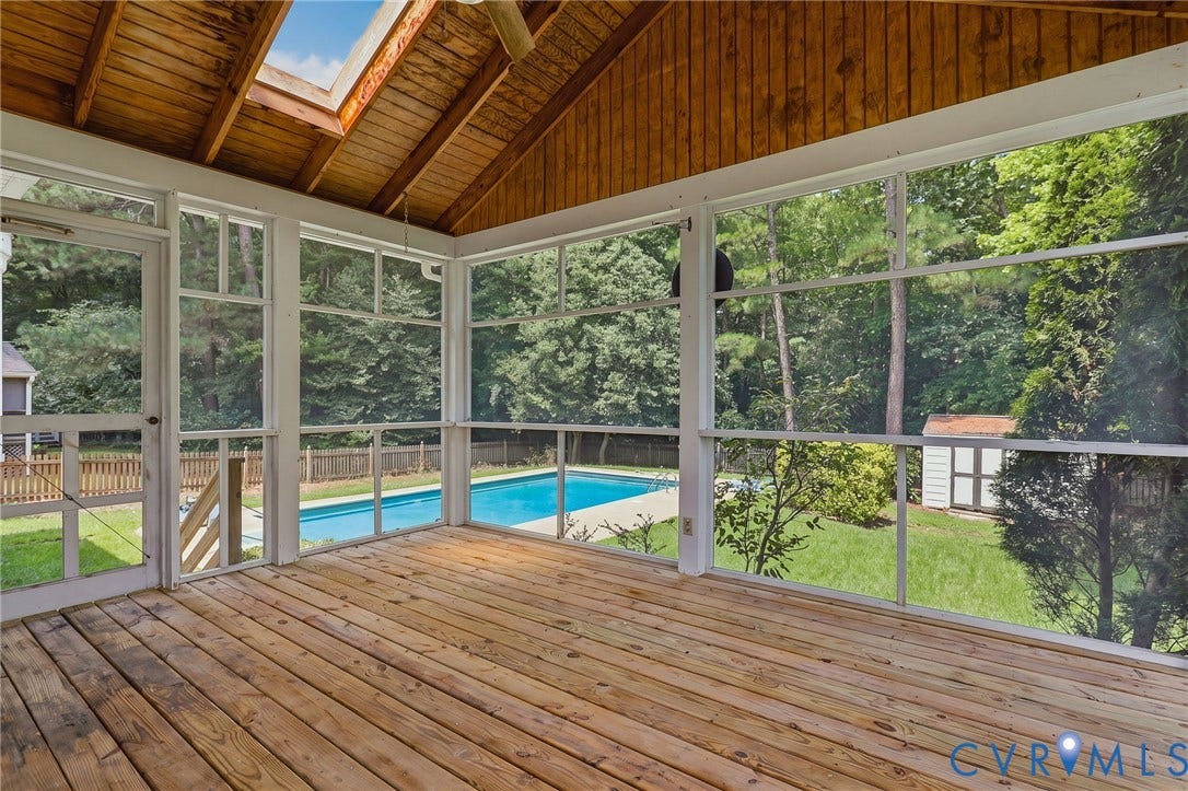 Screened porch featuring skylights and peaceful views overlooking the backyard and pool