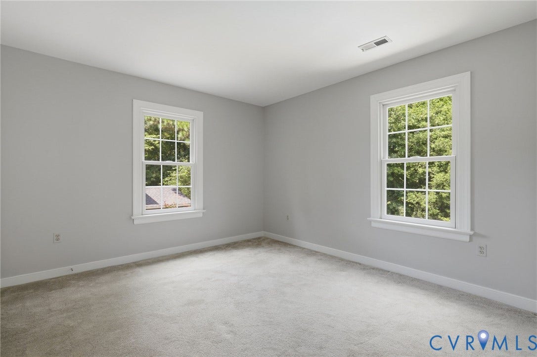 Freshly painted second bedroom featuring abundant natural light and views of the backyard and pool