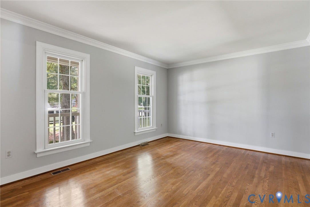 Oversized living room featuring hardwood floors, fresh paint, crown molding, and abundant natural light