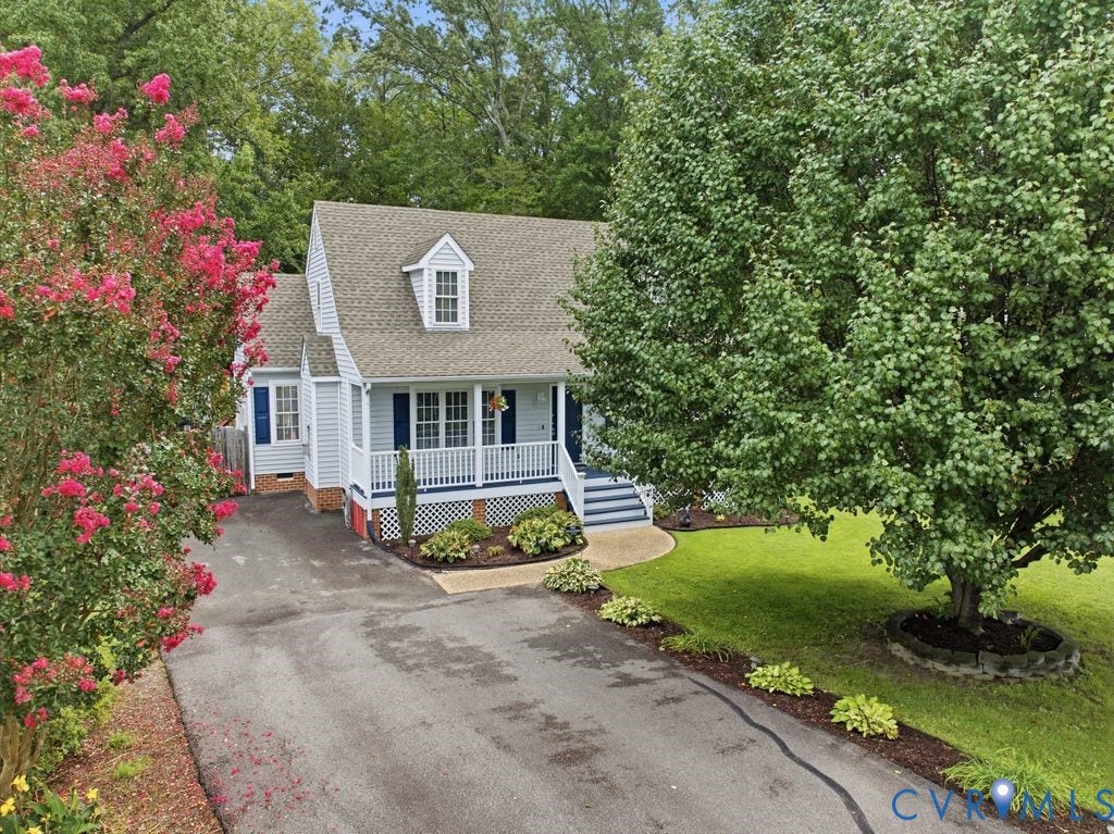 9437 Willow Ridge Drive, Glen Allen, VA 23060 Light blue siding exterior with white trim, a covered front porch with white railings, a dormer window, mature trees, and a paved driveway
