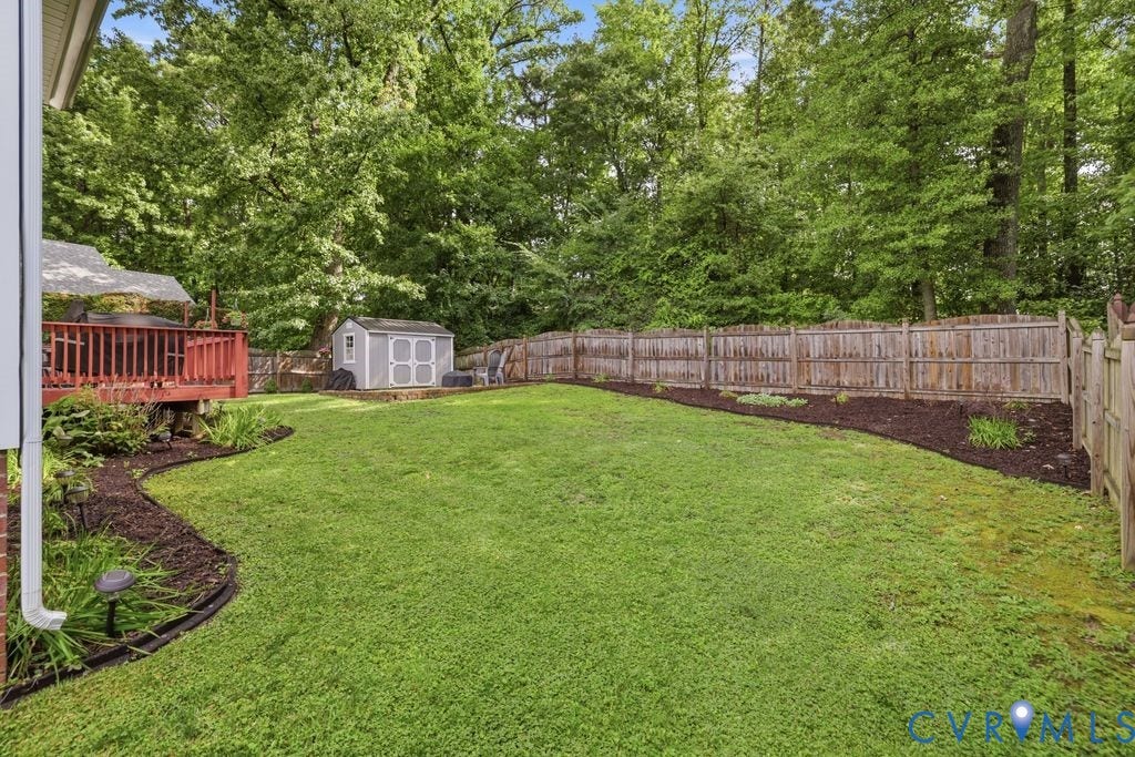 9437 Willow Ridge Drive, Glen Allen, VA 23060 Expansive green lawn, wood deck, fenced perimeter, storage shed, and landscaped garden beds