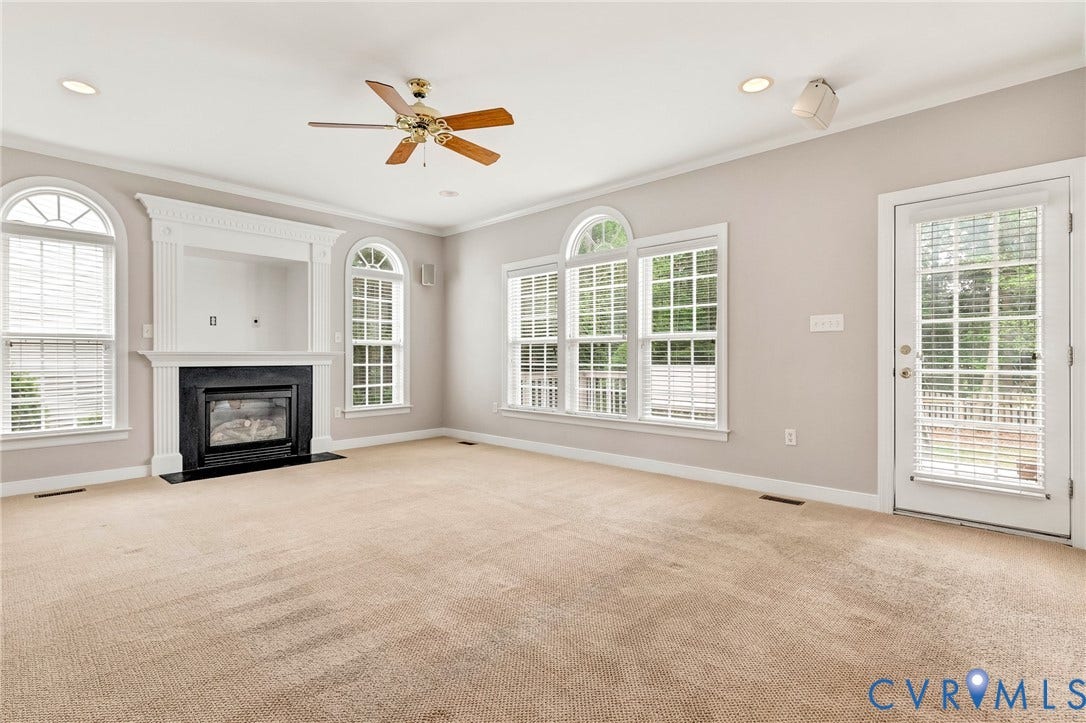 There is now new carpet in this room!!!This cozy room features a gas fireplace with a black surround and white mantel, multiple large windows with arch-top transoms, a ceiling fan, recessed lighting, and a glass-paneled exterior door to the deck.
