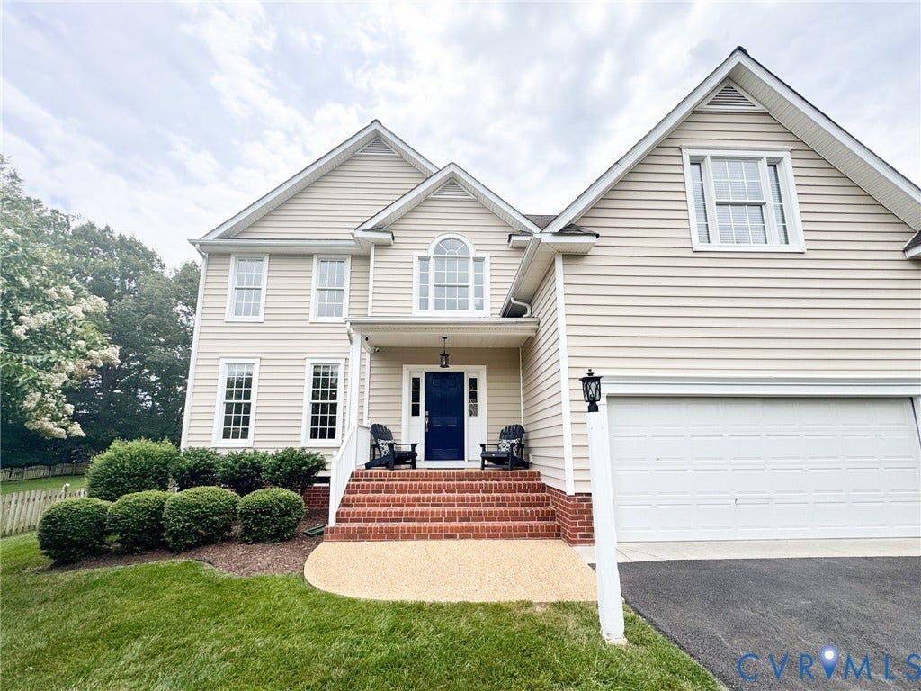 4805 Saddleridge Court, Saddleridge At Twin Hickory, Glen Allen, VA 23059 Two-story residence featuring light-colored siding, a prominent dark blue front door, an arched window above the entry, a two-car garage, and a brick-front porch with steps