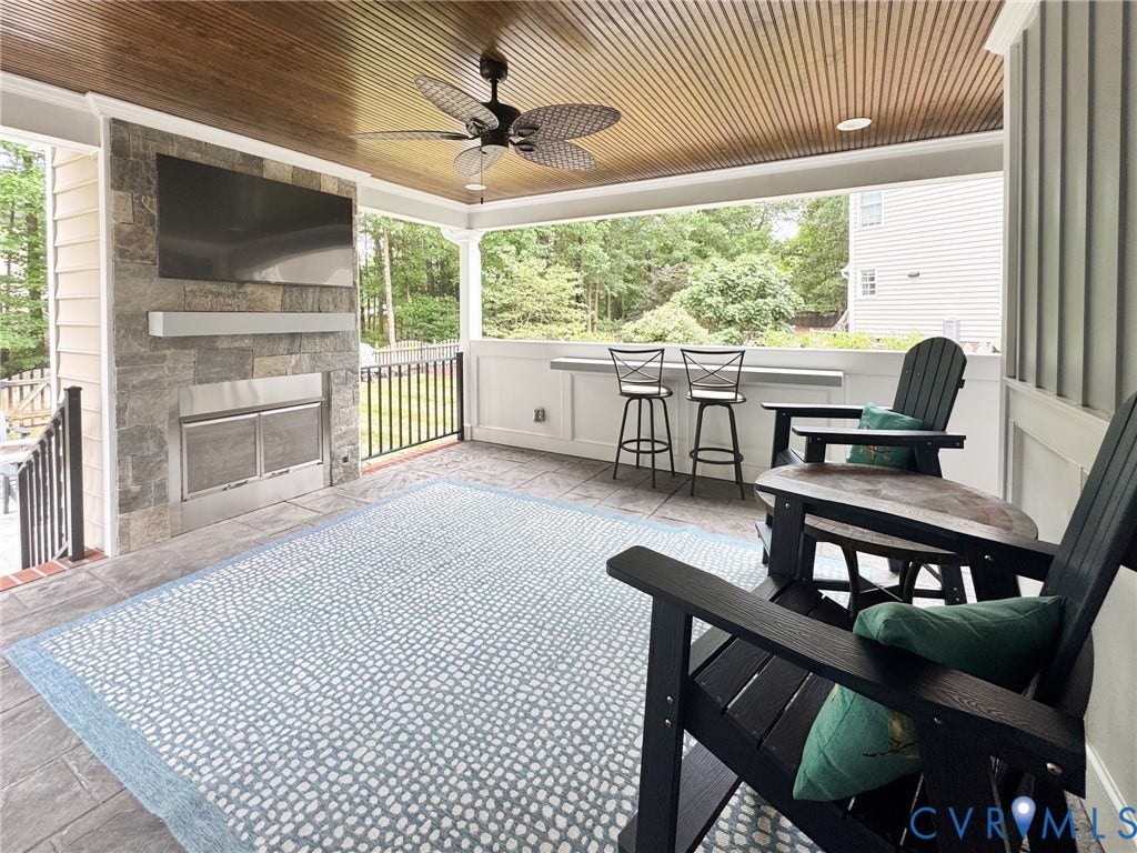 4805 Saddleridge Court, Saddleridge At Twin Hickory, Glen Allen, VA 23059 Covered outdoor porch featuring a wood-finish slatted ceiling, stone-clad fireplace with a built-in outdoor television, ceiling fan, and tiled flooring