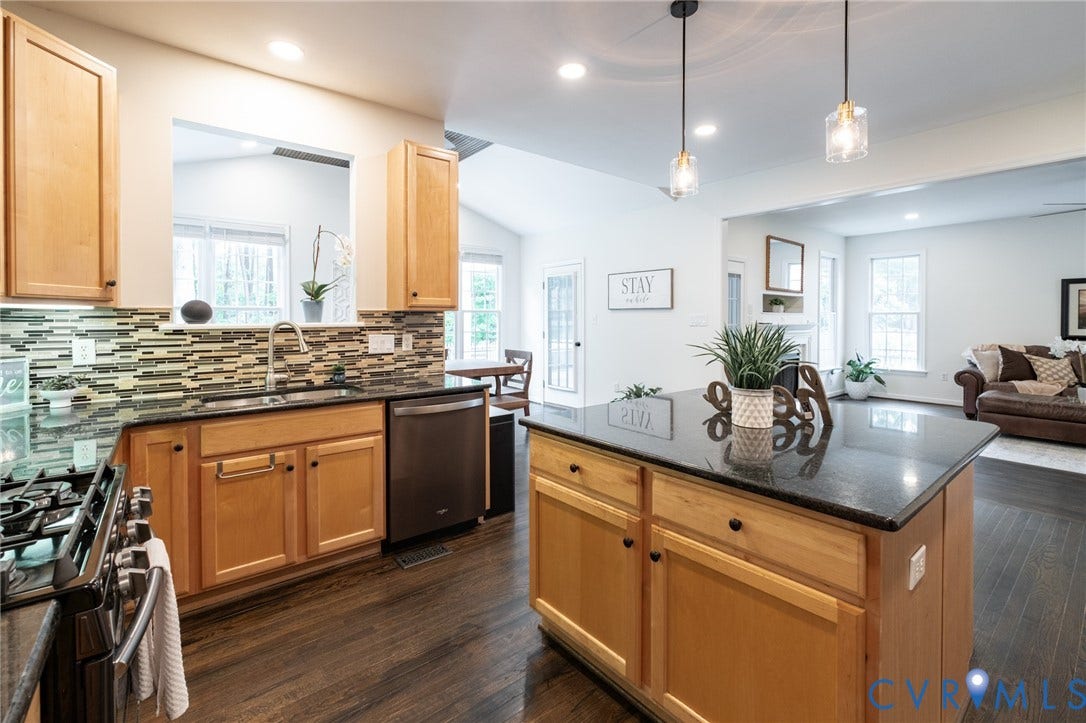 4805 Saddleridge Court, Saddleridge At Twin Hickory, Glen Allen, VA 23059 Open concept kitchen featuring an island with a black countertop, wood cabinetry, stainless steel appliances, and a mosaic tile backsplash