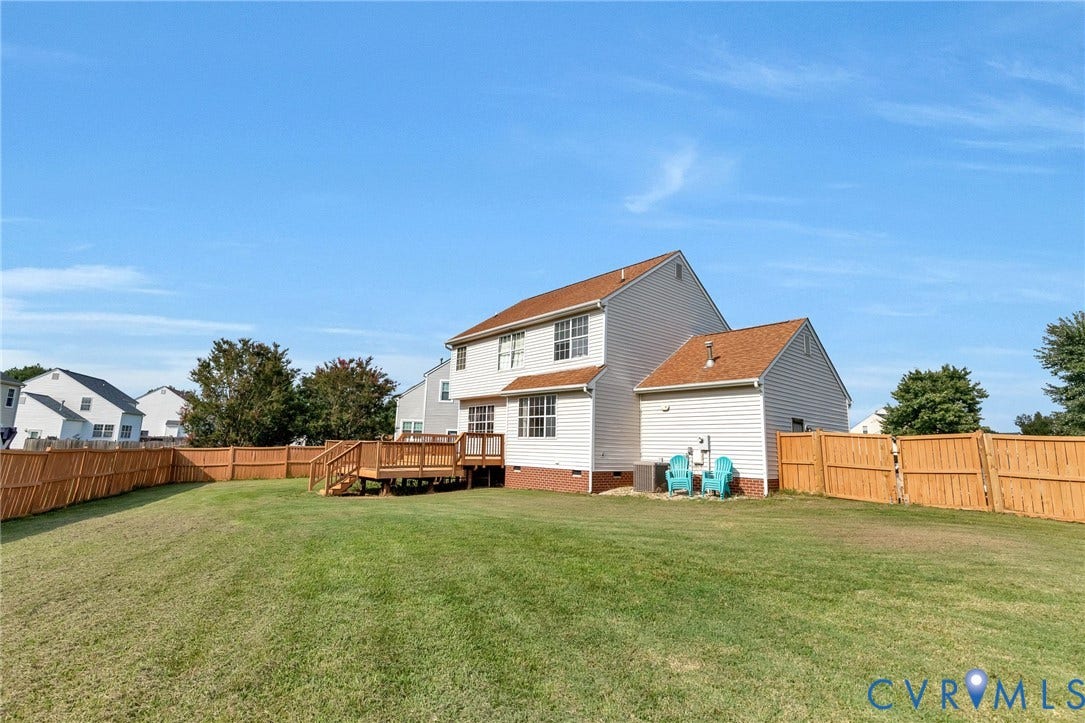 1601 Varina Station Court, Henrico, VA 23231 Expansive fenced backyard featuring a wood deck with stairs, a manicured lawn, and mature trees