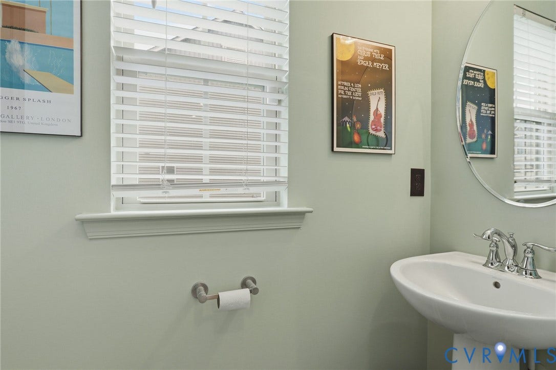 10653 Braden Parke Drive, Midlothian, VA 23832 Pedestal sink featuring a chrome faucet, round mirror, and a window with blinds