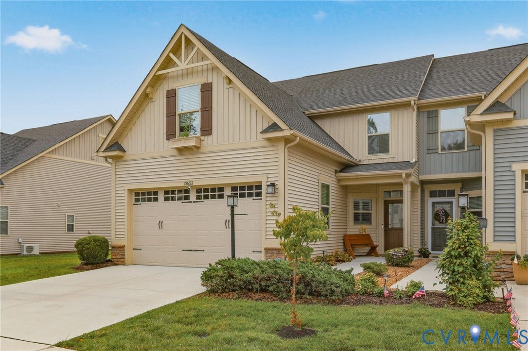 10653 Braden Parke Drive, Midlothian, VA 23832 Townhome exterior featuring tan siding with stone accents, an attached garage, a covered front entry, and mature landscaping