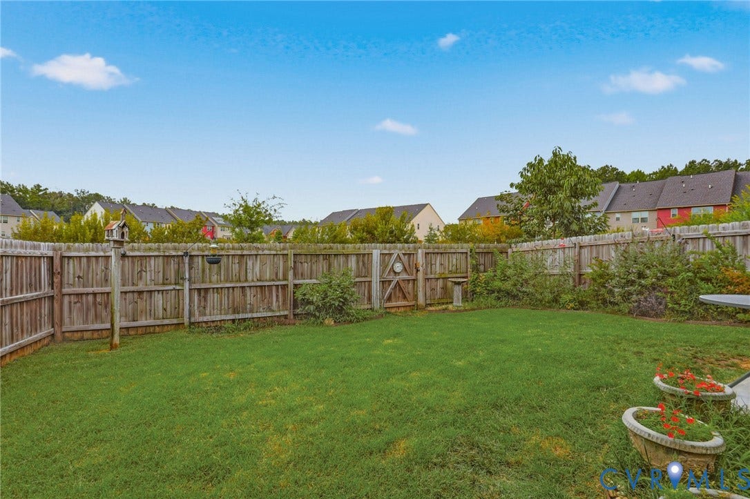 10653 Braden Parke Drive, Midlothian, VA 23832 Expansive lawn area enclosed by a wooden privacy fence, featuring a wooden gate and established perimeter shrubs