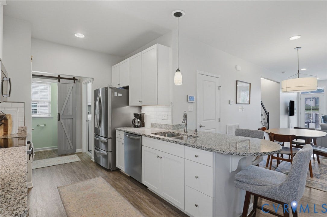 10653 Braden Parke Drive, Midlothian, VA 23832 Modern kitchen featuring a large island with a stone countertop, white shaker cabinetry, stainless steel appliances, and wood-finish flooring