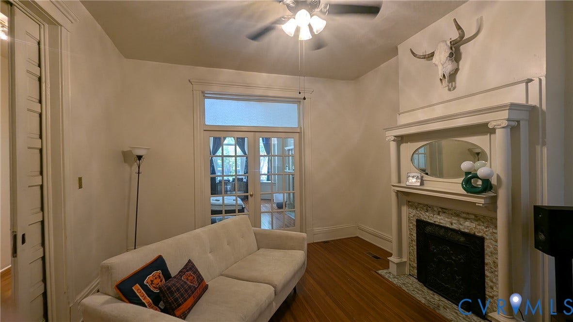 1620 Grove Avenue, #1, Richmond, VA 23220 Living area featuring a detailed fireplace mantel with a patterned stone surround, wood-finish flooring, a ceiling fan with integrated lighting, and double French doors with transom window