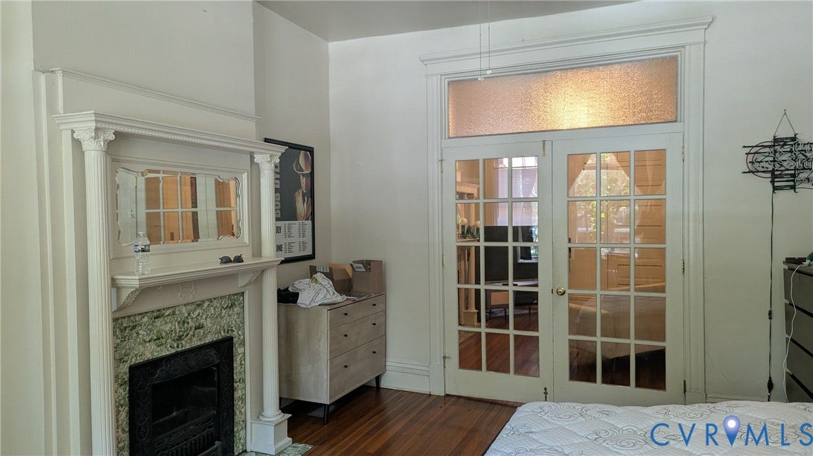 1620 Grove Avenue, #1, Richmond, VA 23220 Architectural fireplace with a green-veined stone surround and white mantel, complemented by classic French doors with a frosted transom window, and wood-finish flooring