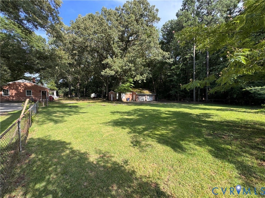 Expansive grassy yard area with mature trees providing partial shade